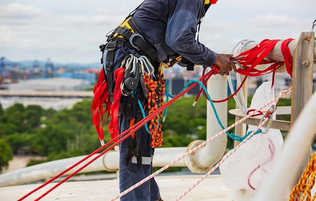 Closeup male worker standing on tank male worker height roof\
tank knot carabiner rope