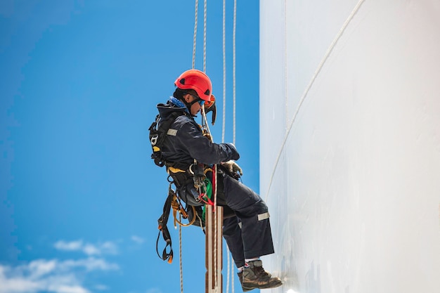 クローズ アップ男性労働者タンク男性労働者高さ屋根タンク ノット カラビナ ロープ アクセス安全にスイングします。