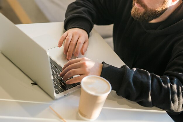 Closeup man chatting in social networks skilled freelancer enjoying remote job typing publication for web blog on laptop top view