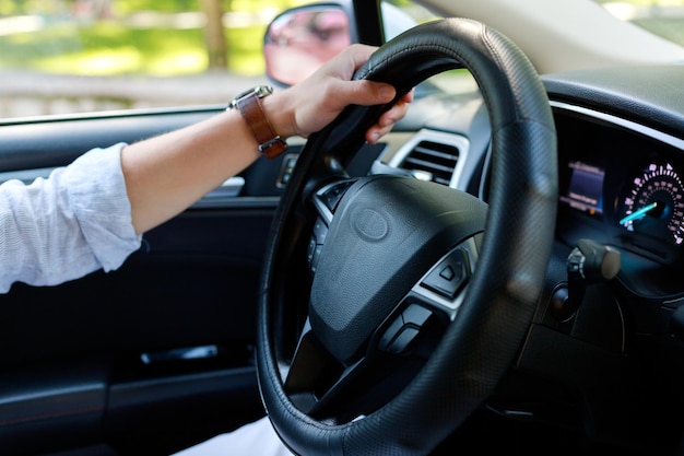 Closeup man drives a car with one hand