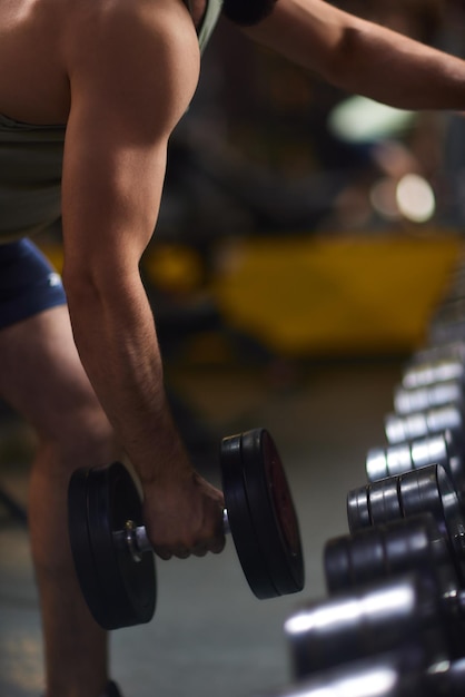 Closeup man grabs a heavy dumbbell in gym with his hand concept lifting fitness