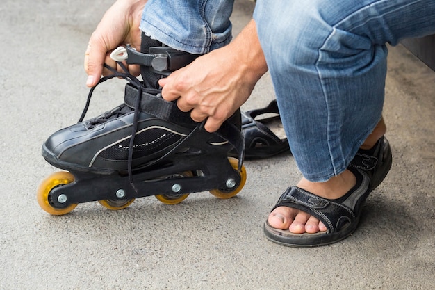 Closeup of man guy putting on roller skates outdoor