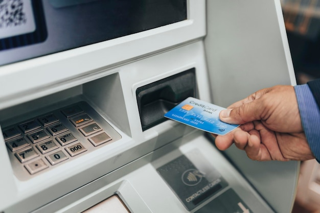 Closeup of man hand inserting ecard into ATM slot