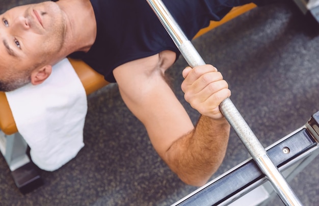 Closeup of man hand lifting a weight barbell on a bench press training in a fitness center