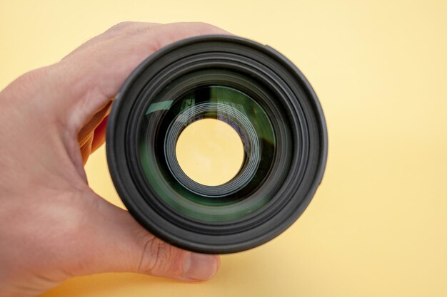 Closeup of a man holding a camera lens in his hand on a background