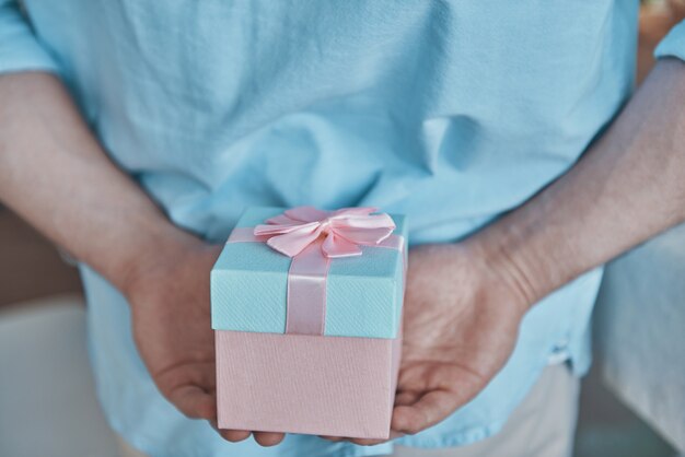 Closeup of man holding gift box behind his back