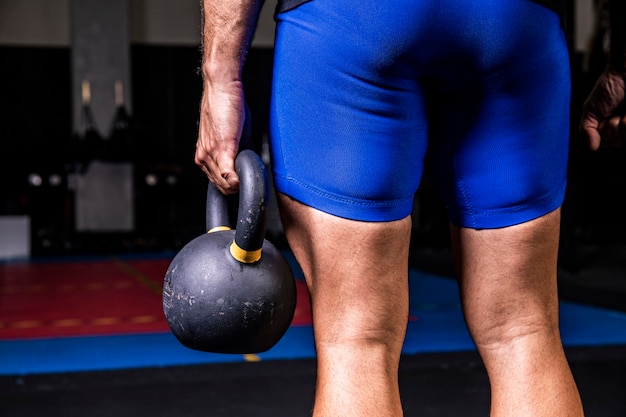 Closeup of man holding heavy kettlebell at the gym