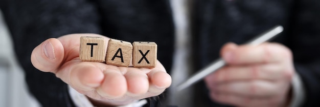 Closeup of man holding on palm tax word collected of wooden blocks letters government state