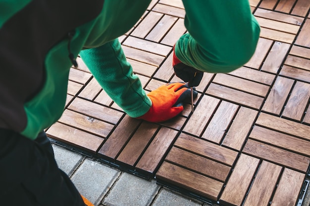 Closeup man installing wood flooring on the terrace at home