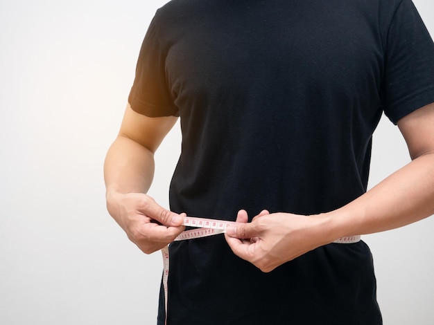 Closeup man met behulp van meetlint lichaam voor het controleren van zijn taille