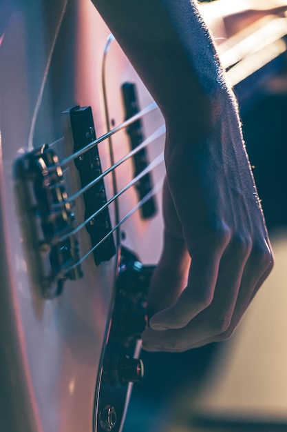 Closeup of a man playing the bass guitar