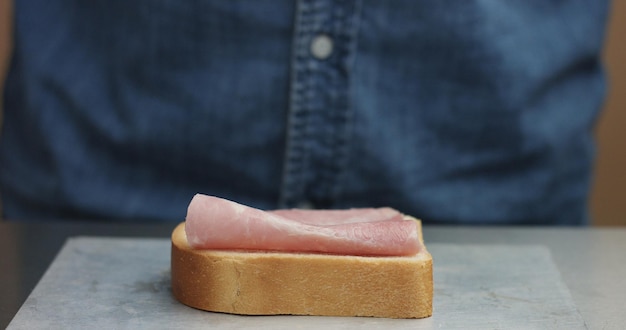 Closeup of man's hand making sandwich puts from sides all ingredients on plate