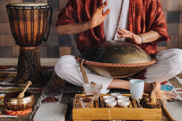 Foto primo piano della mano di un uomo che suona uno strumento musicale moderno il tamburo della lingua di orione durante la cerimonia del tè