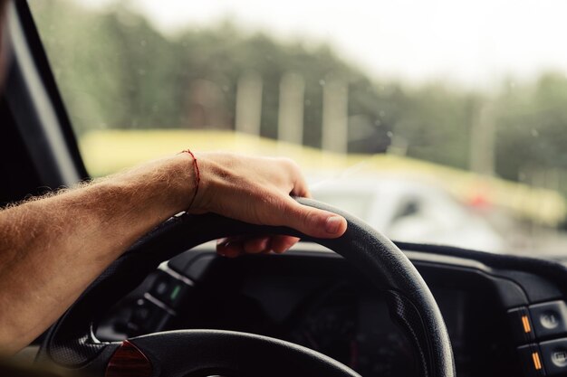 Photo closeup of man's hand on steering wheel driving a car