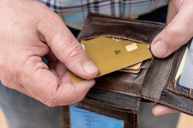 Крупный план мужской руки, вынимающей кредитную карту из держателя личного документа