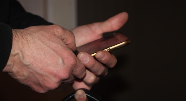 Closeup of Man's Hand Touching Screen of Smartphone in the dark