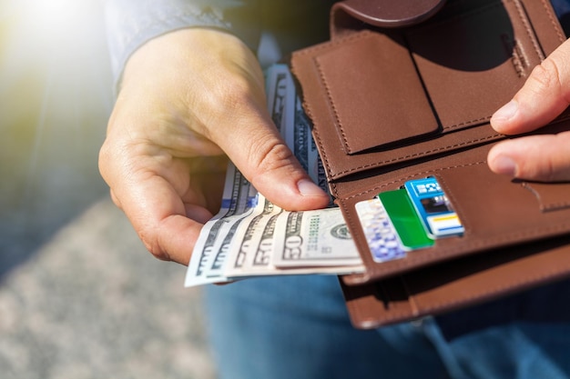 Closeup on a man's hands as he is getting a banknote out of his walletxAxA