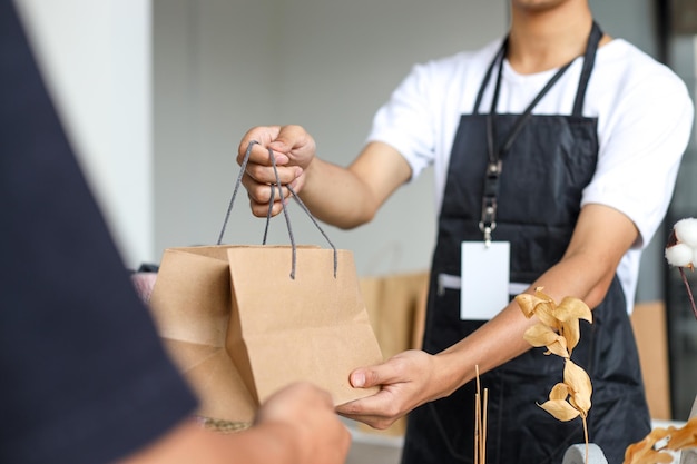 買い物袋を持った店で顧客にサービスを提供する男性のクローズアップ