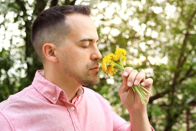 Closeup of a man smelling the scent of dandelions