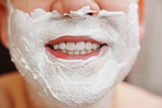 Closeup man smiling with foam for shaving on his face