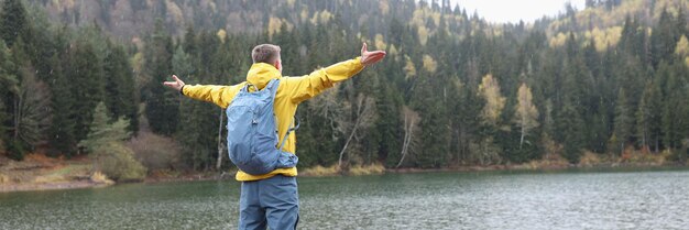 Closeup of man traveler with backpack standing at lake and mountains landscape Freedom adventures and travel concept