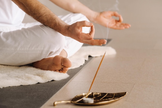 Closeup of a man in white sportswear doing yoga in a fitness room with a balgovon the concept of a healthy lifestyle