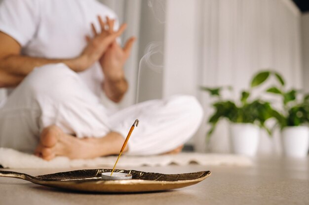 Closeup of a man in white sportswear doing yoga in a fitness room with a balgovon the concept of a healthy lifestyle