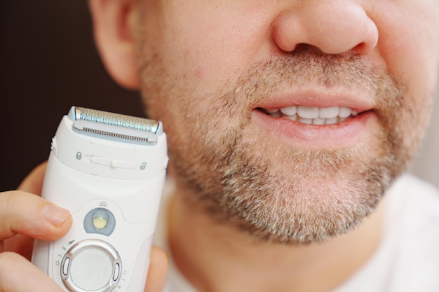 Closeup a man with bristles holding an electric razor trimmer