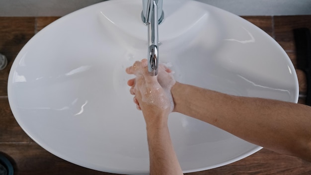 Closeup mannelijke handen wassen in grote witte gootsteen thuis in badkamer in hotel dagelijkse hygiëne lichaamsverzorging