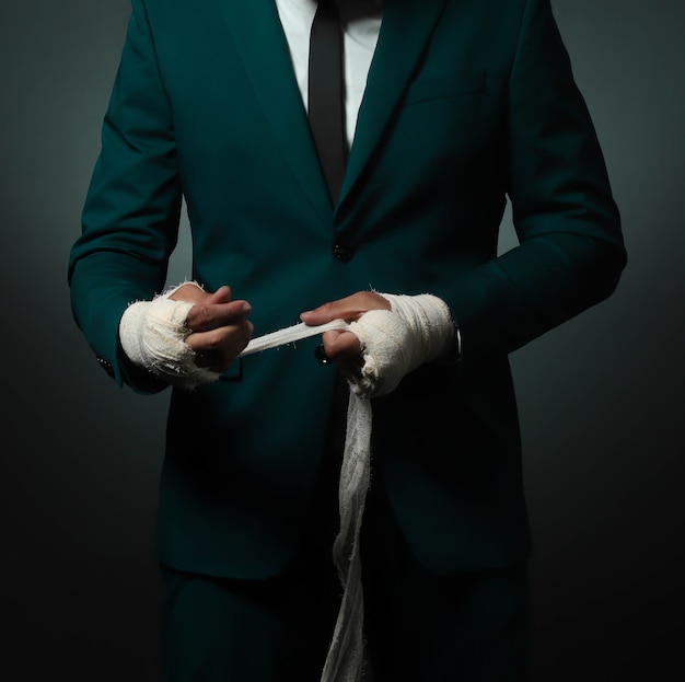 Closeup mannenhand van zakenman vechter in pak met pleisters en gebalde vuisten.