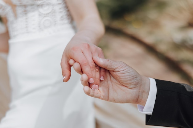 Closeup of a mans hand holding a womans hand Gentle touch The groom holds the hand of the bride