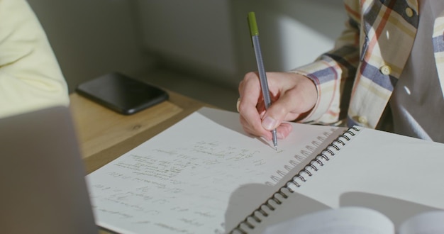 Closeup of a mans hand making notes in a notebook the face is not visible