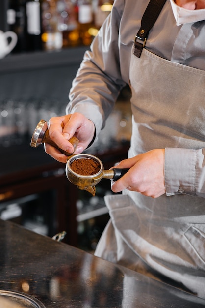 카페 바에서 맛있는 커피를 준비하는 마스크 바리 스타의 근접 촬영 전염병 동안 레스토랑과 카페의 작업