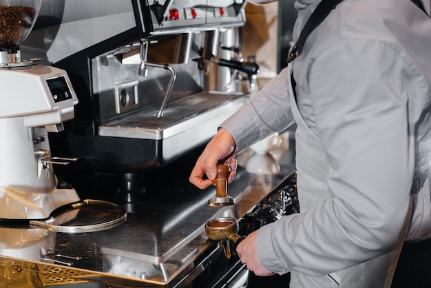 Primo piano di un barista mascherato che prepara un delizioso caffè al bar in una caffetteria