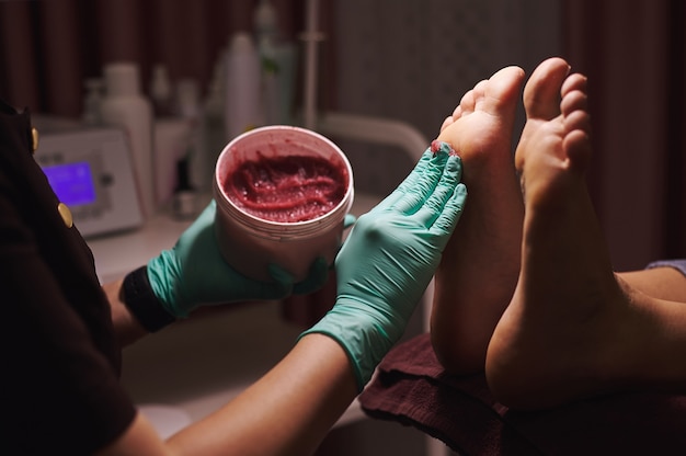 Closeup of massaging foot with a foot scrub during a\
professional pedicure in beauty salon