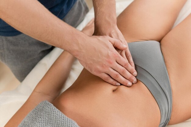 Closeup of masseur man's hands during stomach massage for his woman client