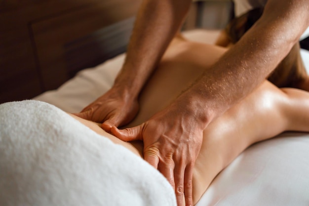 Closeup of masseur's hands doing back massage to young woman