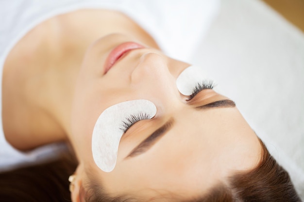 Closeup master of eyelash extensions extends eyelashes to a beautiful woman