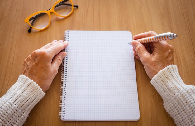 Primo piano delle mani della donna matura con la scrittura della penna sul taccuino