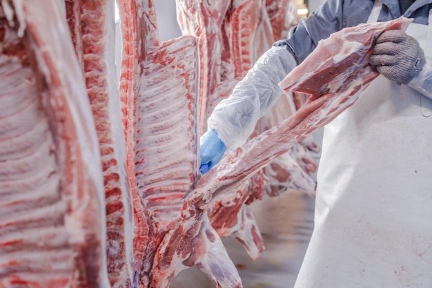 Closeup of meat processing in the food industry a worker cuts raw pork the concept of meat products