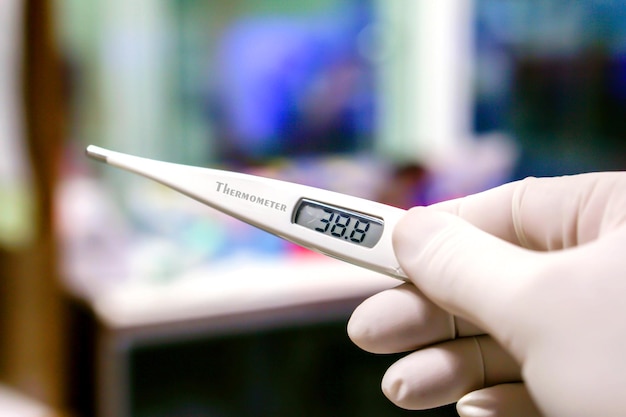 Closeup Medical thermometer in hands of doctor on blurry background