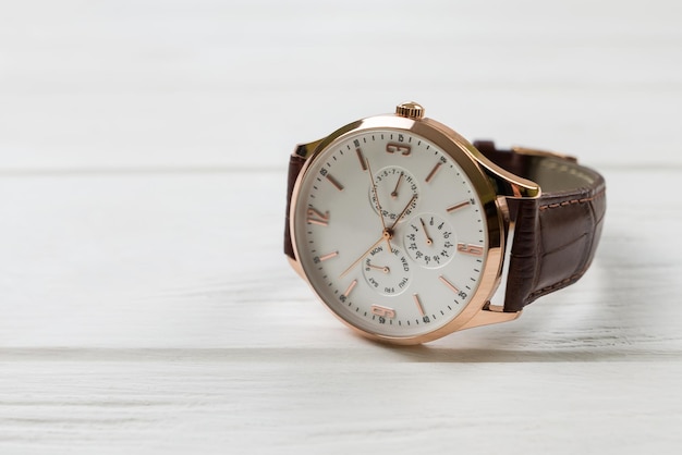 Closeup of a men's wrist watch on a white wooden background
with copy space mechanical wrist watch with a brown strap