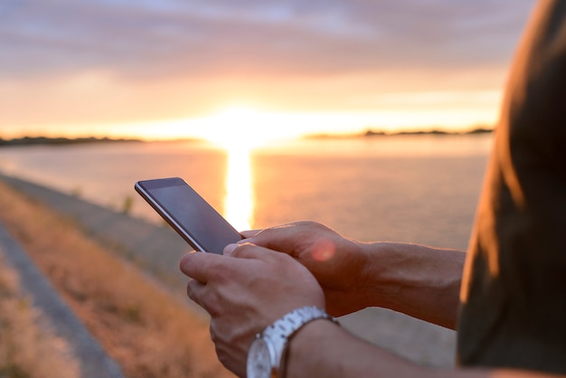 Closeup men using smartphone at sunset