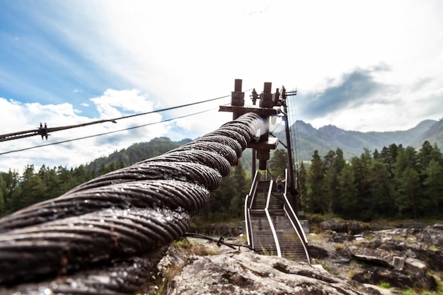 Closeup on a metal binding cable going in perspective to the bridge support with the texture of a summer sunny day Reliability and strength concept architecture