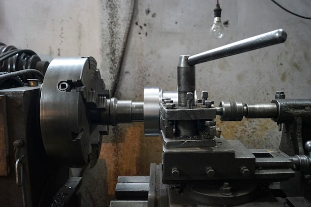 古い旋盤機械旋盤チャックとキー 4jaw スクリュー チャックによる金属シャフト部品切削のクローズ アップ古い工場でビンテージ産業機械
