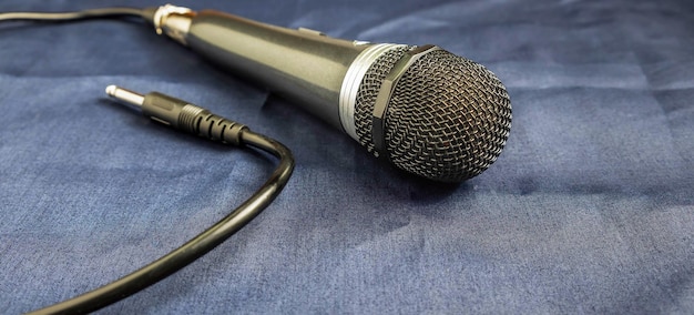 Closeup of microphone connected by cable on blue background