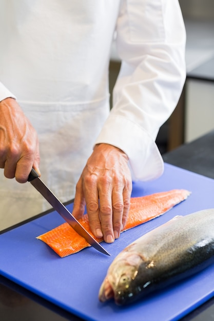 Photo closeup mid section of a chef cutting fish