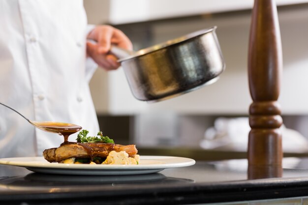 Photo closeup mid section of a chef garnishing food
