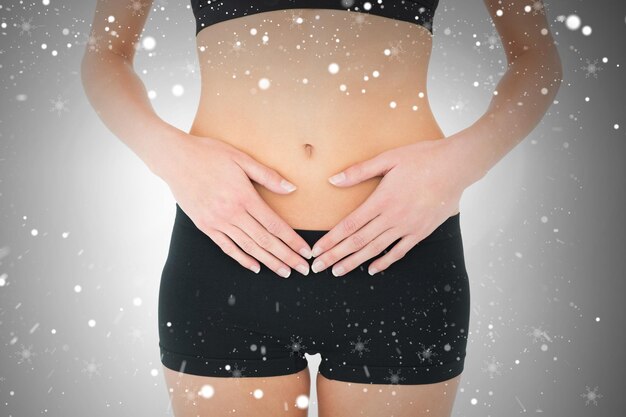 Photo closeup mid section of a fit woman with stomach pain against snow