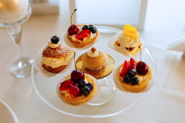 A closeup of mini cakes on a transparent cake stand on a table